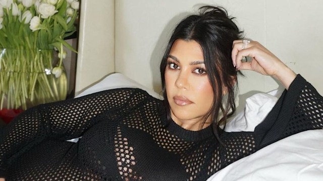 Kourtney Kardashian pregnant relaxing on bed wearing black mesh dress