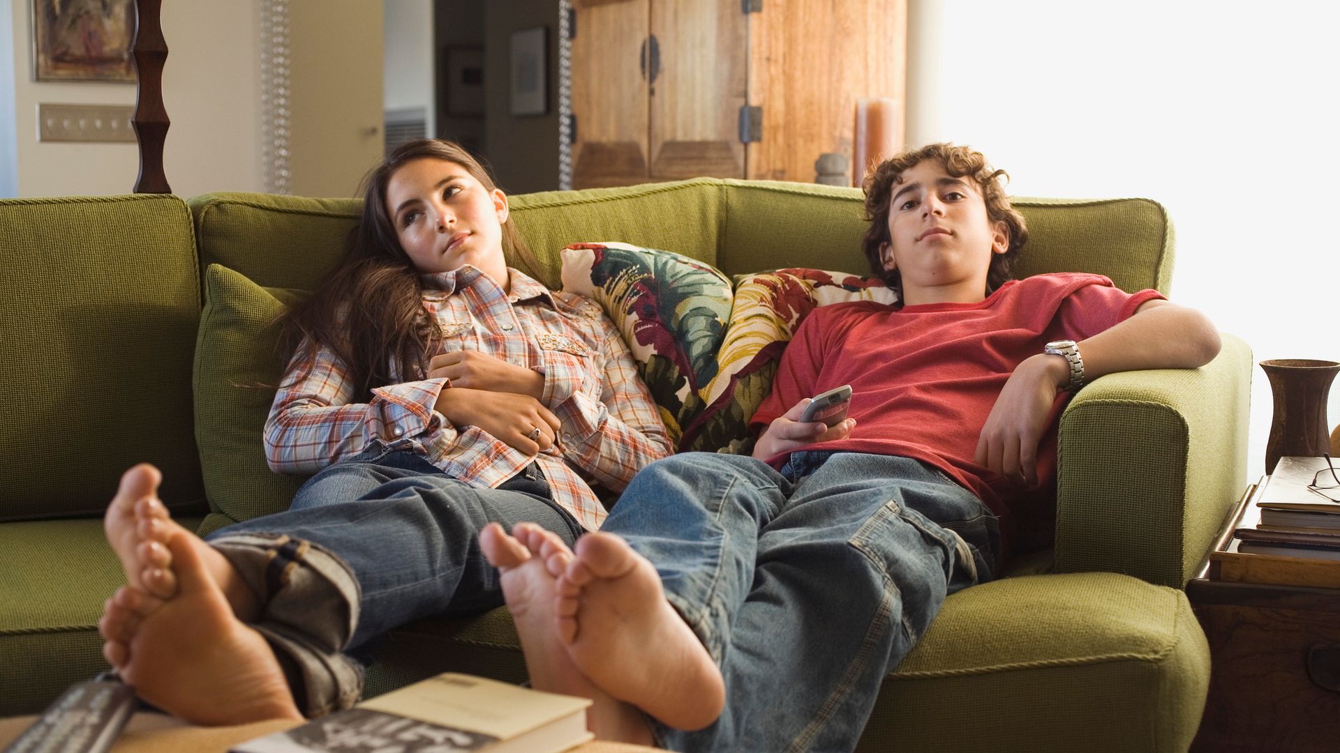 Boy and girl sitting on sofa with remote control