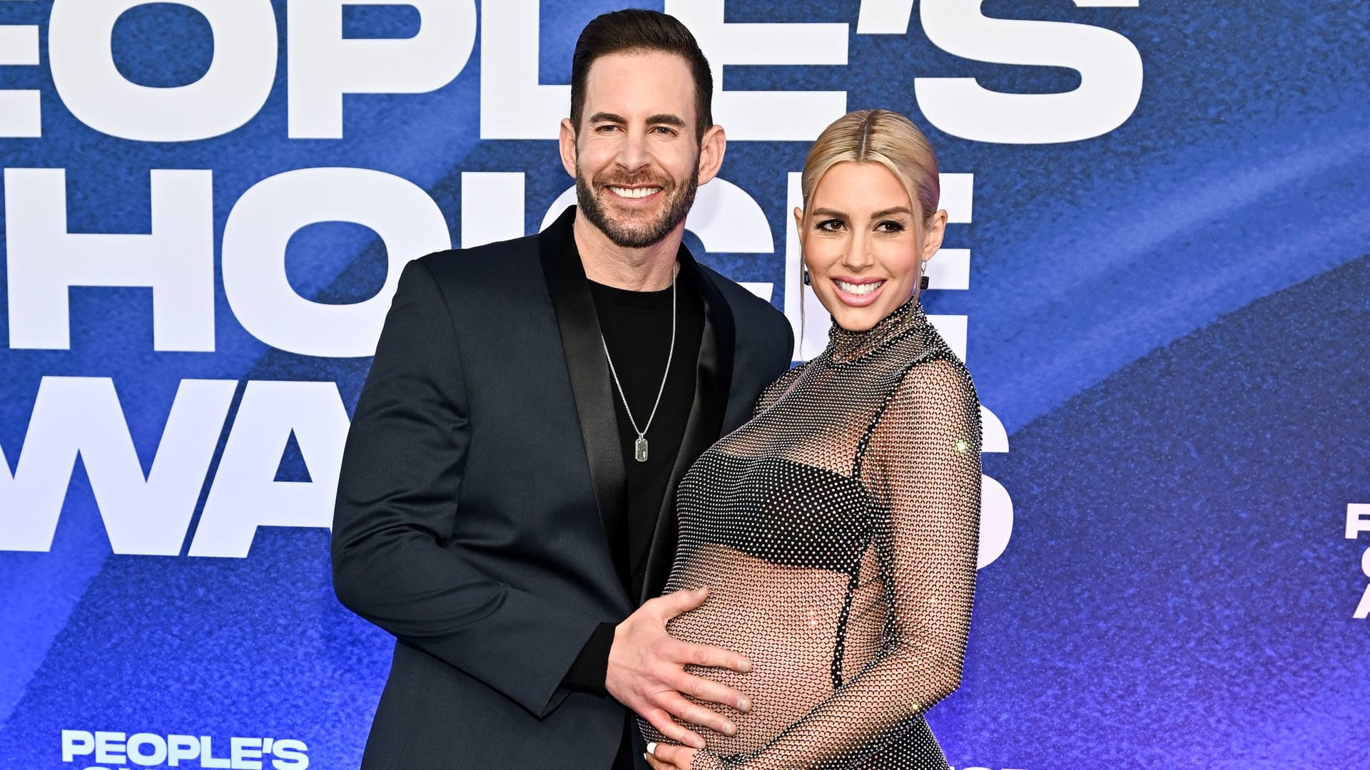 A pregnant Heather Rae El Moussa with her husband Tarek on a red carpet