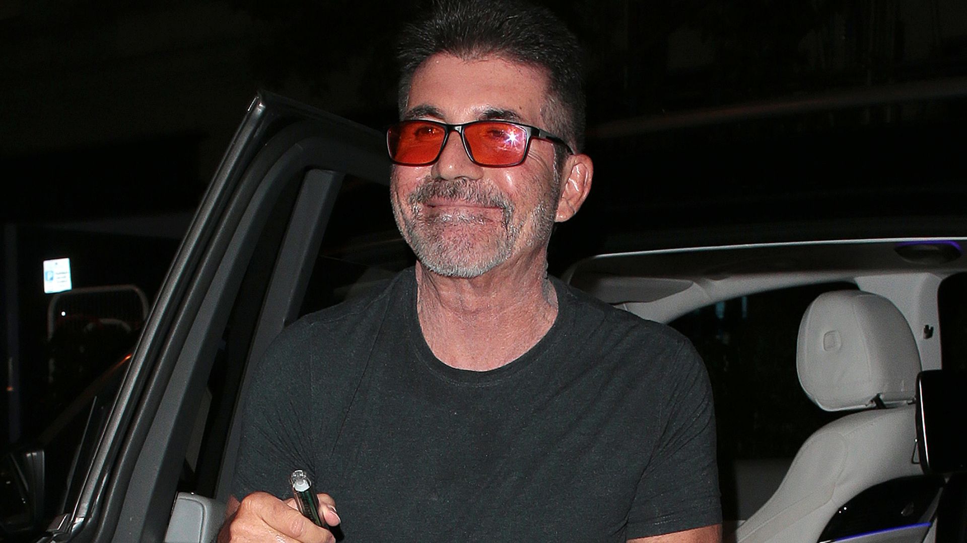 Simon Cowell getting out of a car wearing orange glasses