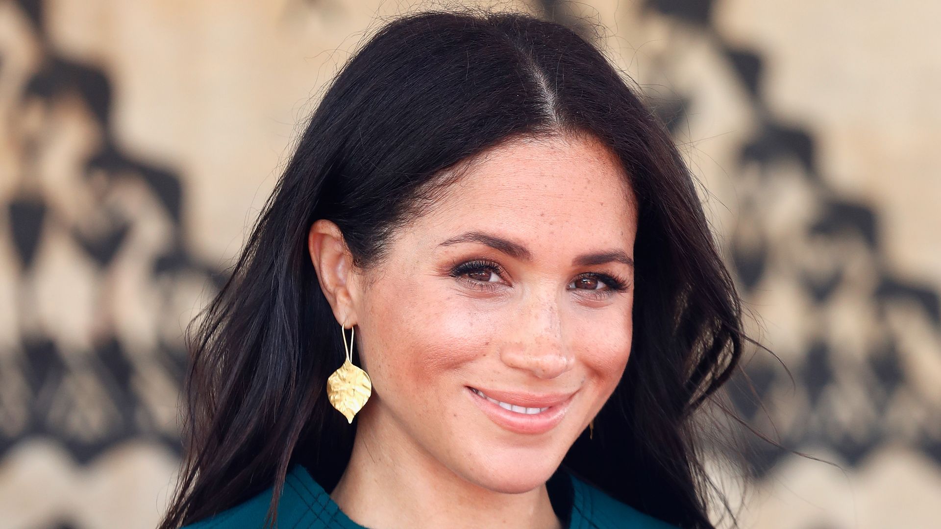 Meghan, Duchess of Sussex smises in teal dress