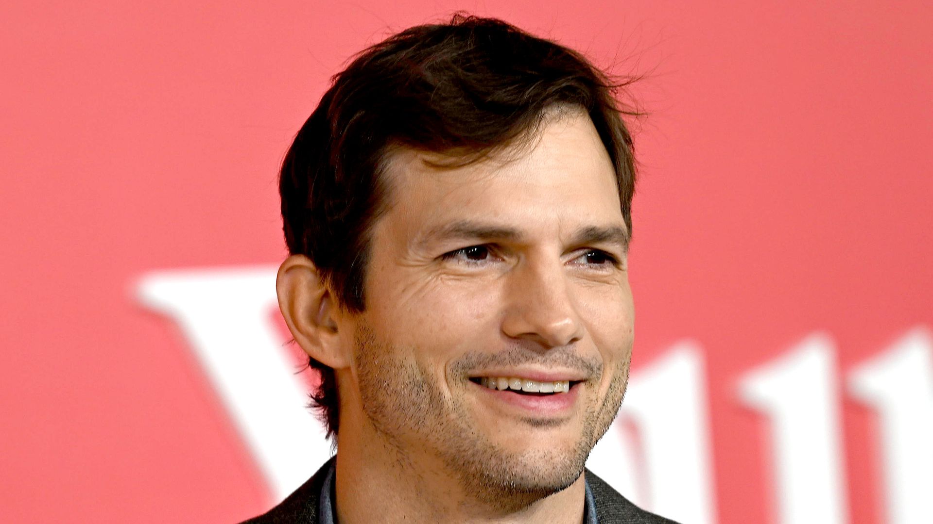 Ashton Kutcher in grey jacket on red carpet 