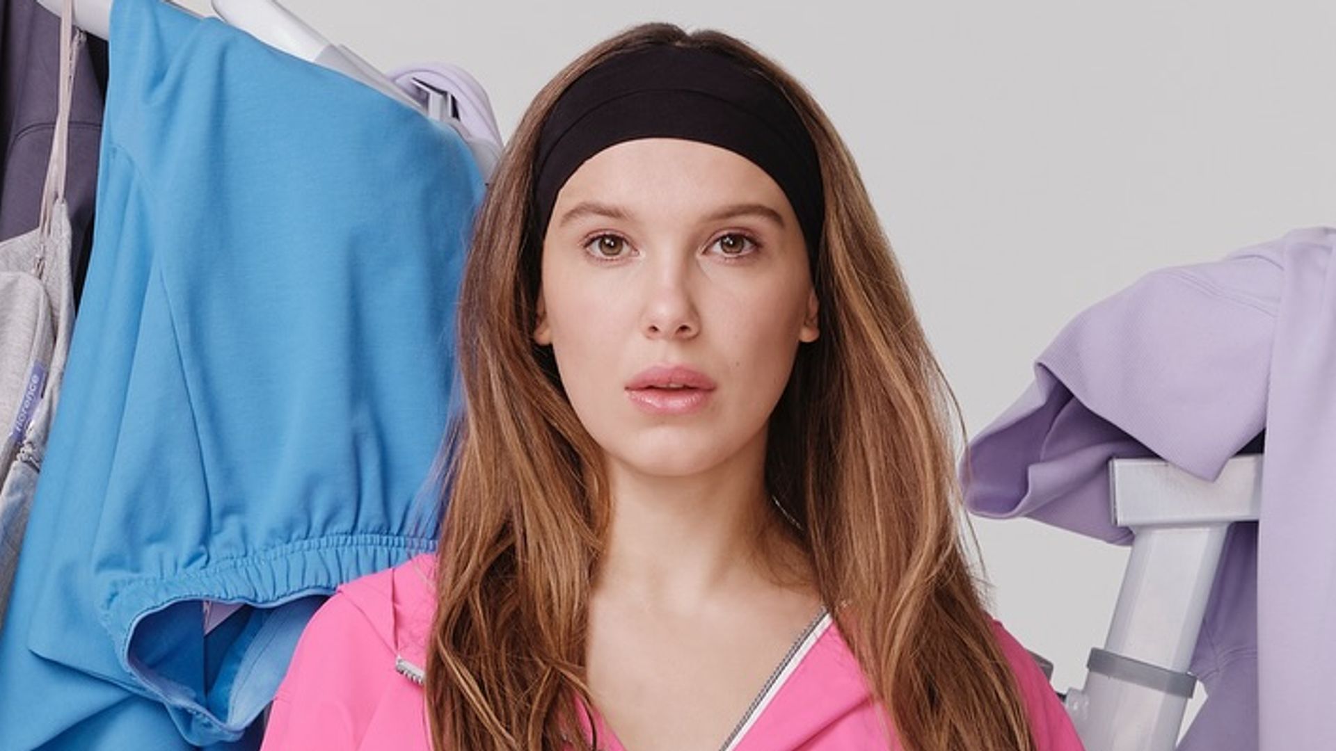 Millie Bobby Brown poses for a photo in a pink tracksuit with her dog