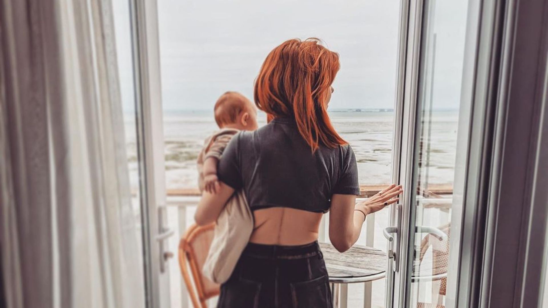stacey dooley holding daughter minnie on terrace overlooking sea