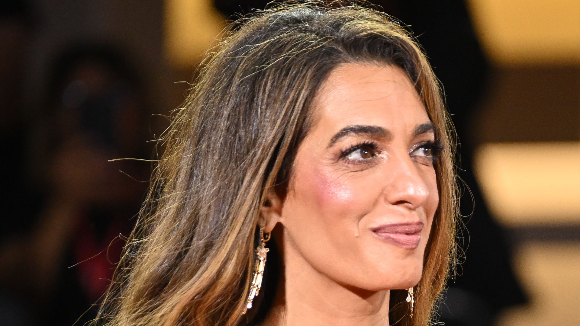 Amal Clooney in purple dress and George Clooney in suit on red carpet 