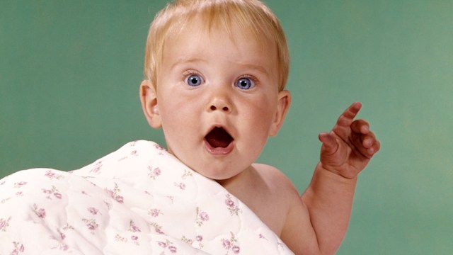 baby with shocked expression under blanket