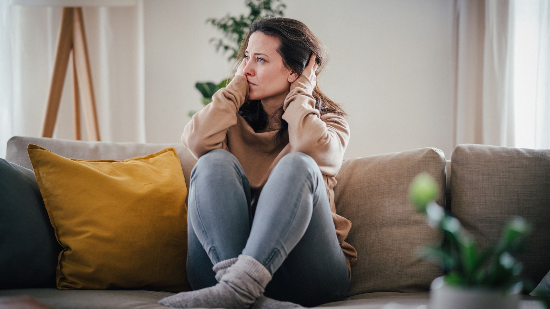Anxious woman sitting on the couch experiencing a panic attack.