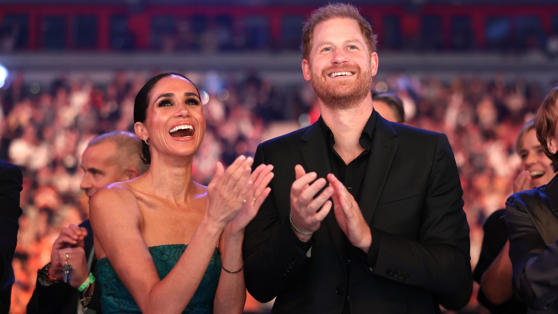 Meghan Markle and Prince Harry clapping whilst looking at the stage
