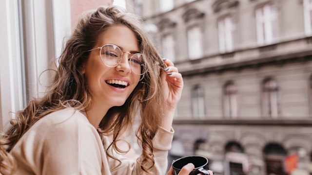 woman smiling as she looks out of the window