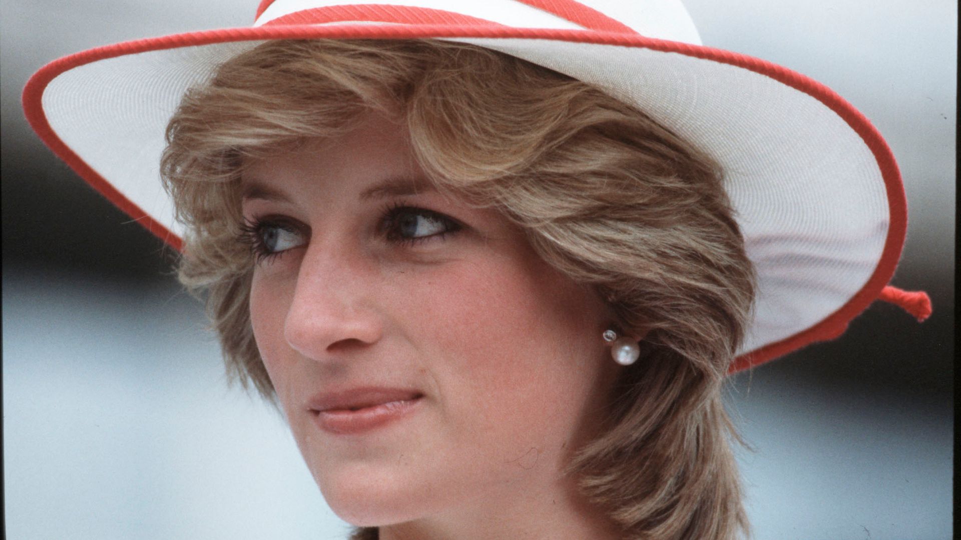Princess Diana on Royal Tour in Canada in 1983, wearing a white and red hat and looking to one side 