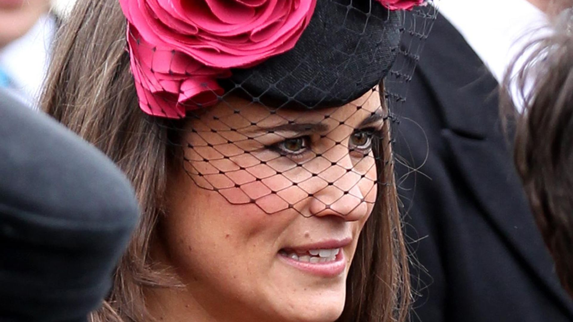 Pippa Middleton side on with black netted fascinator with pink flowers on