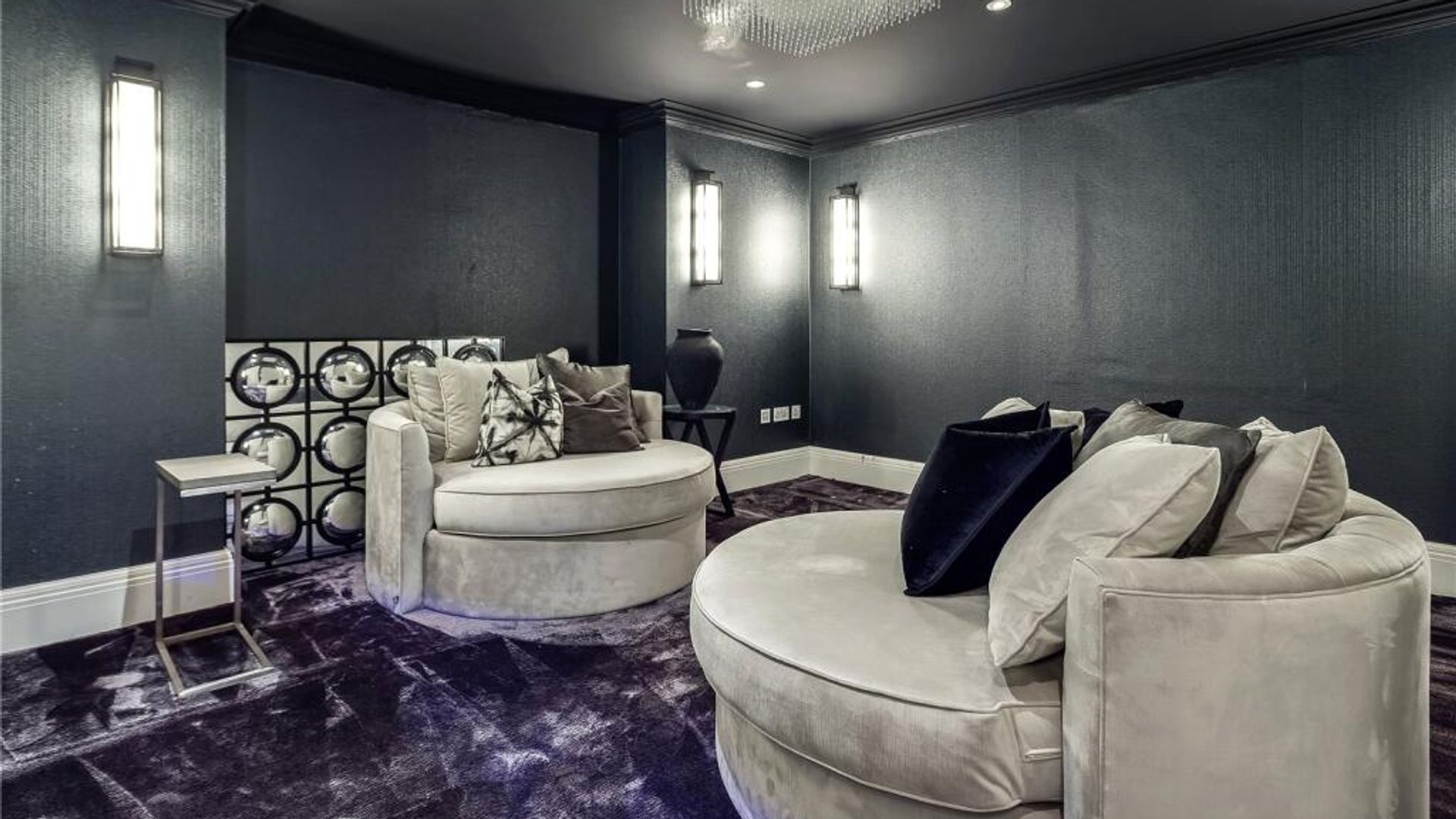 An indoor cinema room with a purple carpet and oversized armchairs