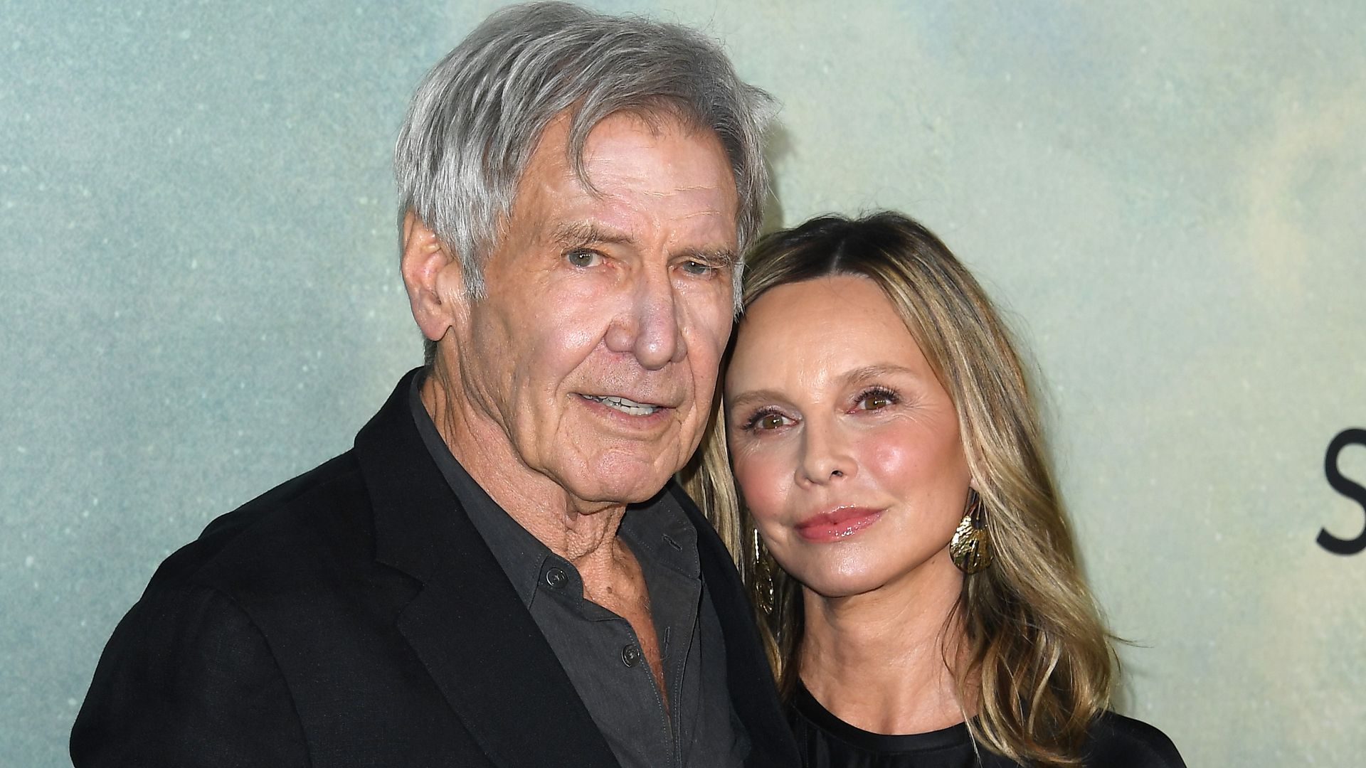 Harrison Ford and Calista Flockhart wearing black smart evening wear standing side by side at the premiere for Apple TV+ Shrinking