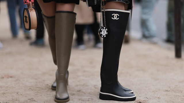 Guests are seen outside Chanel show wearing black silk Chanel headscarfs, black Chanel sunnies, silver and gold Chanel jewelry, colorful Chanel logo cardigan, black Chanel vest and jacket, black and greige Chanel rain boots and small round Chanel handbags during the Womenswear Spring/Summer 2024 as part of  Paris Fashion Week on October 03, 2023 in Paris, France. (Photo by Jeremy Moeller/Getty Images)