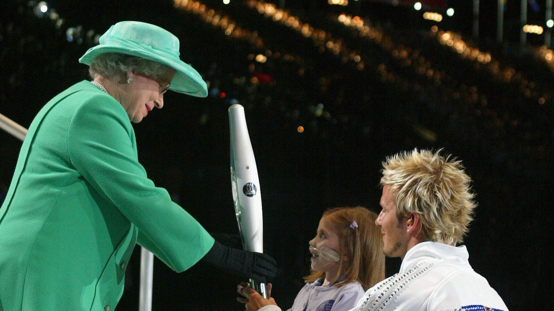 David Beckham and a young girl handing the Olympic torch to the late Queen