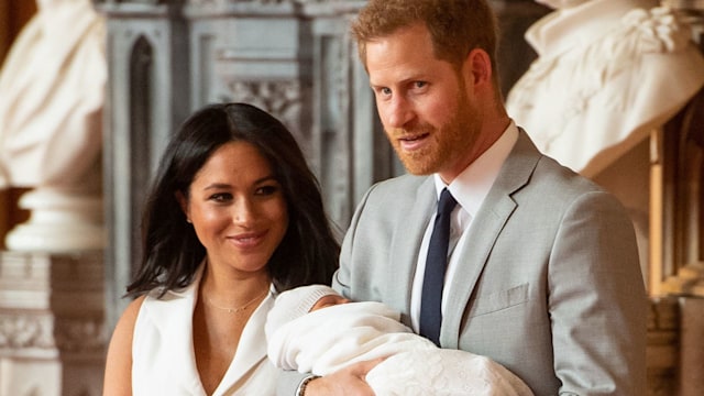 Prince Harry holding baby Archie with Meghan Markle walking next to them