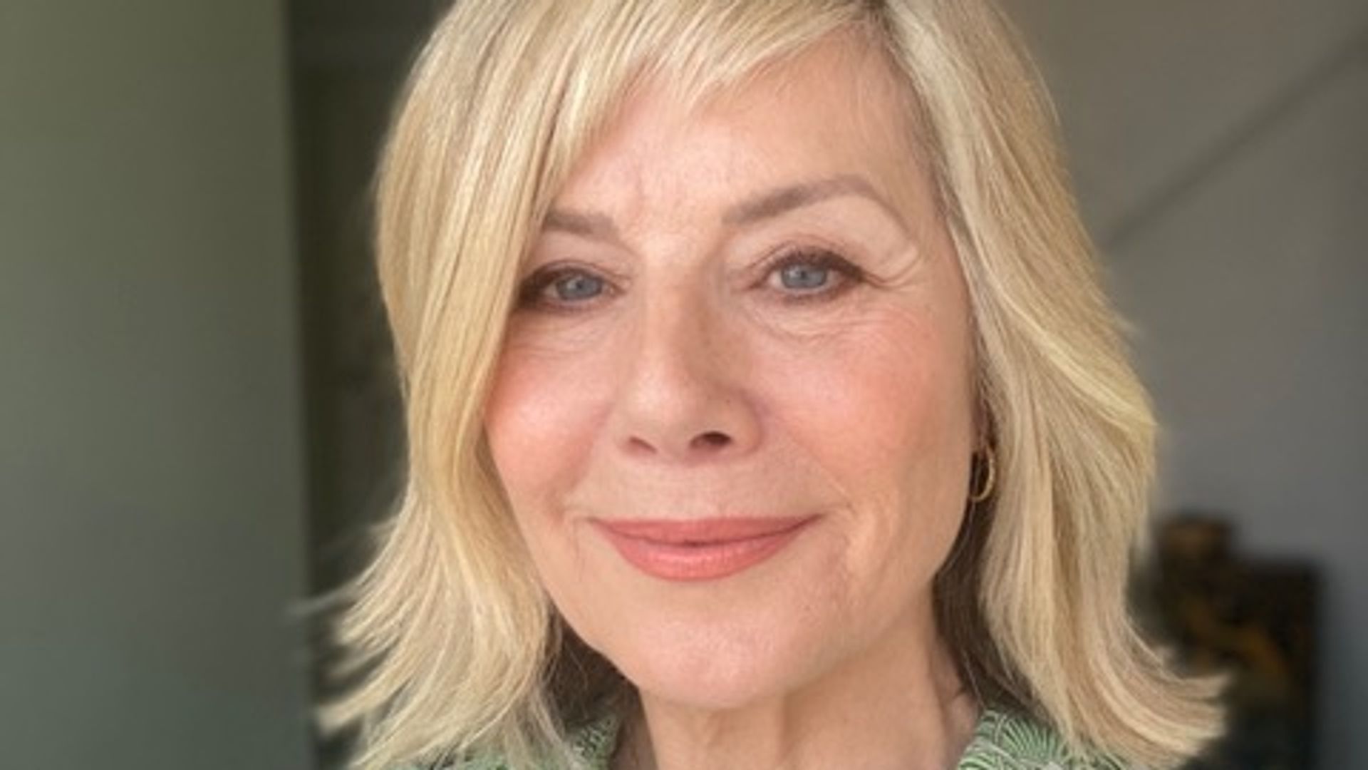 Selfie of a woman in her sixties smiling in a floral print green shirt