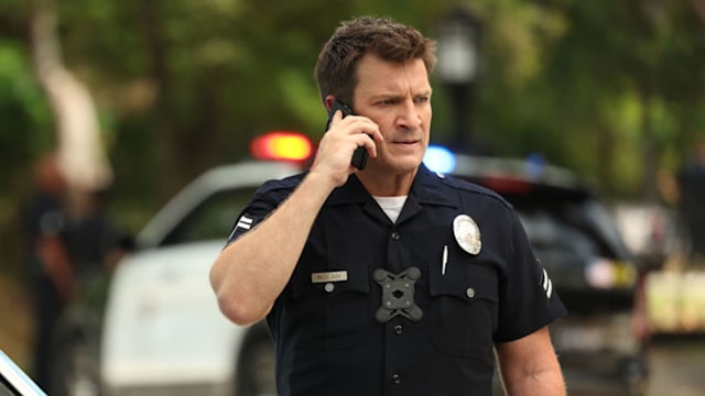 Nathan Fillion as John Nolan in The Rookie, he is answering a phone call. 