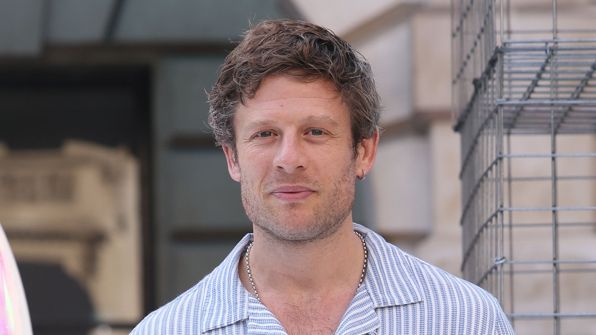 James Norton in white trousers and blue striped shirt