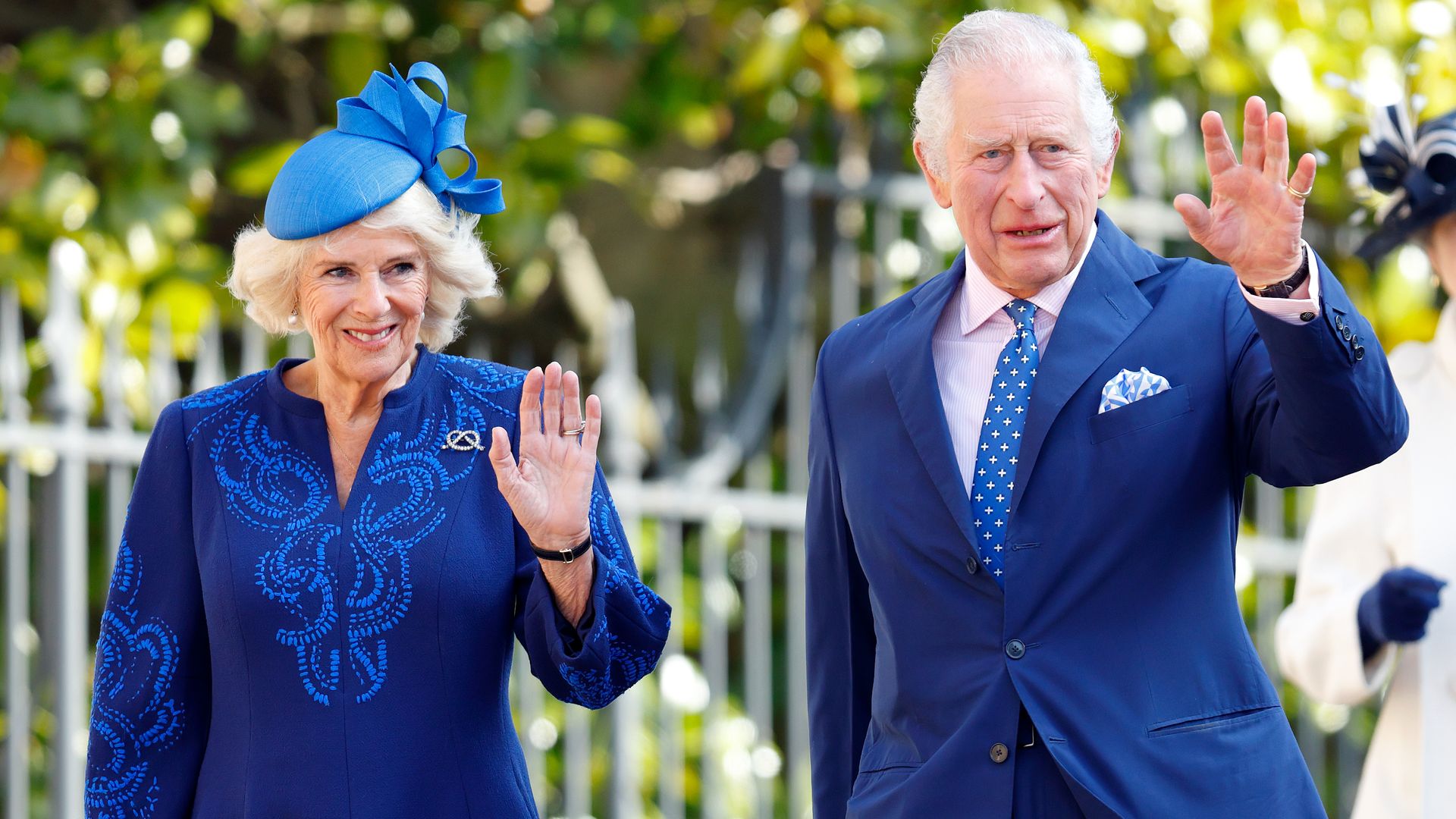 Queen Camilla and King Charles in blue and waving