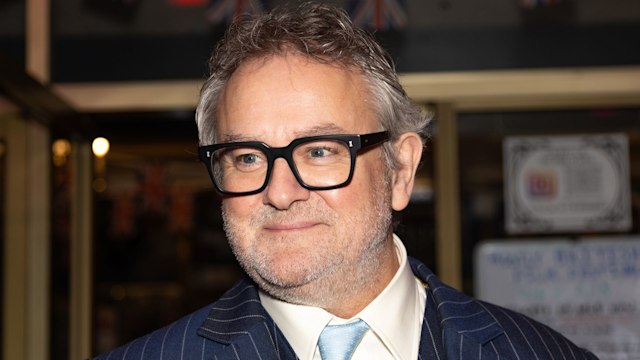 Hugh Bonneville wearing a navy pinstripe suit 