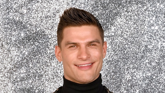 aljaz skorjanec posing against silver glitter backdrop 