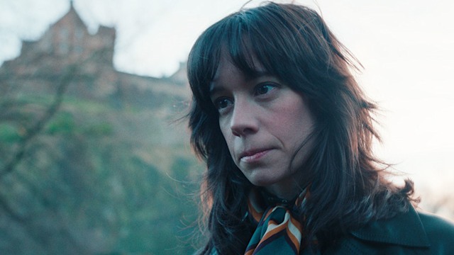 close-up of brunette woman in front of house