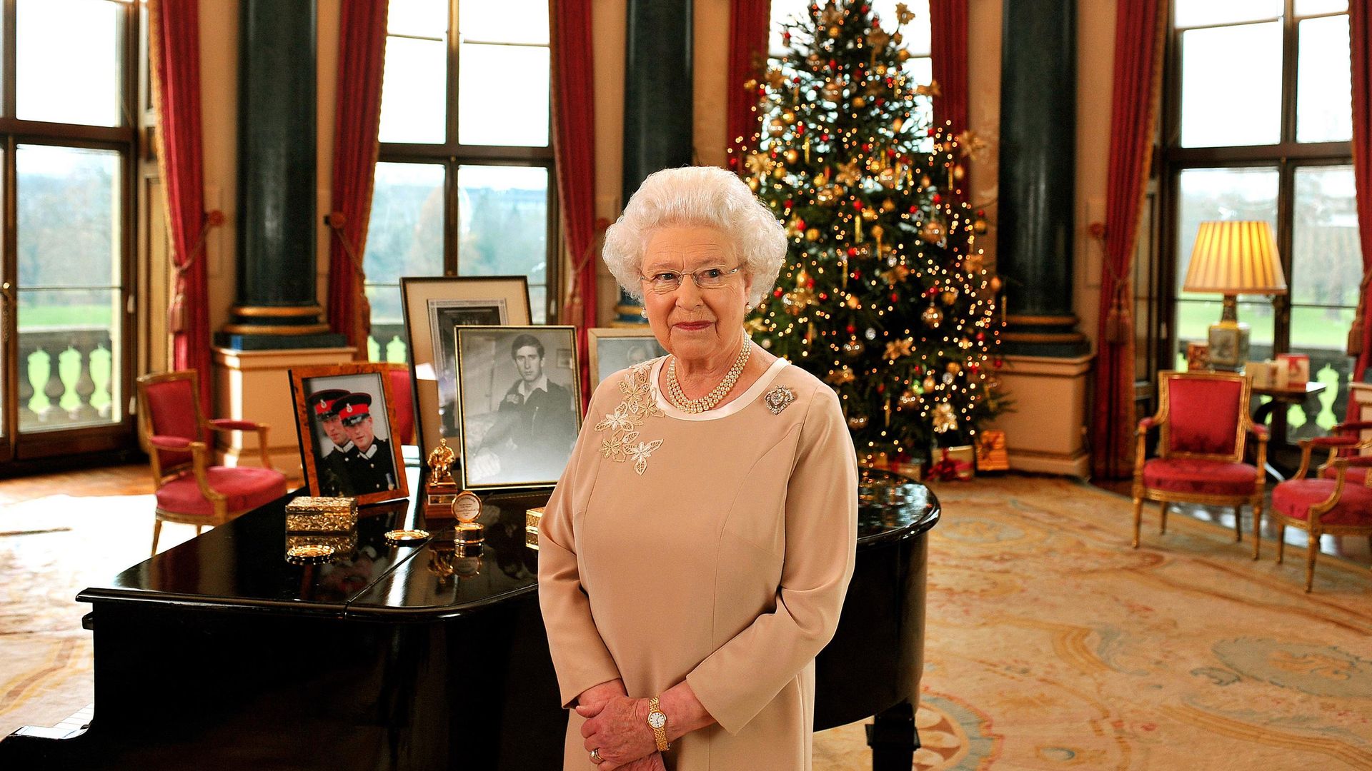 The Queen standing in front of a piano and a Christmas tree