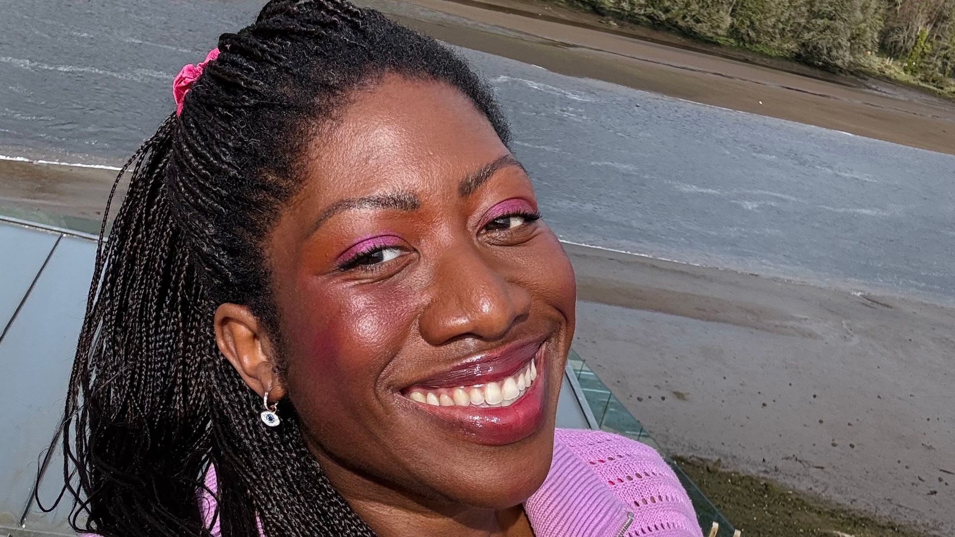 Woman smiling for a selfie on a lake in a purple jumper