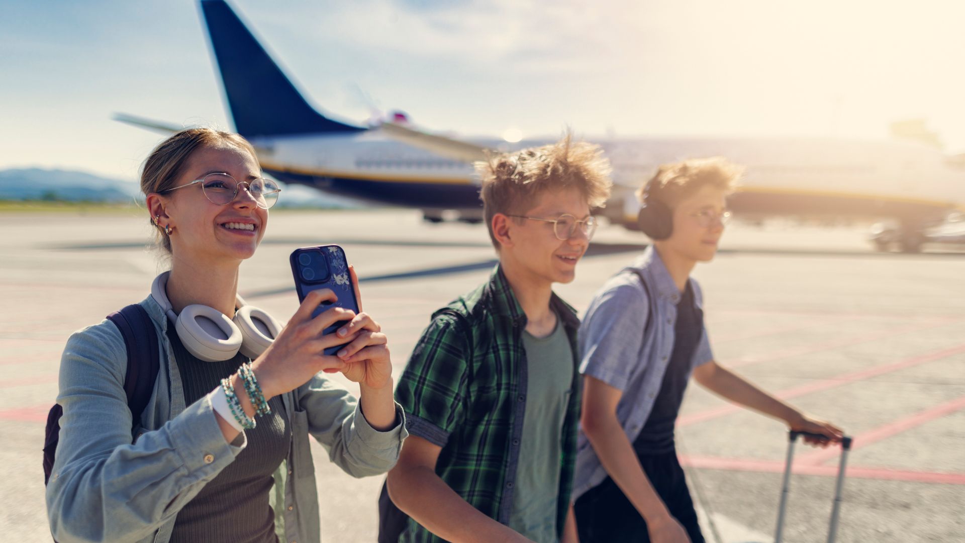 Teenage travelers walking on airstrip after getting out from their plane