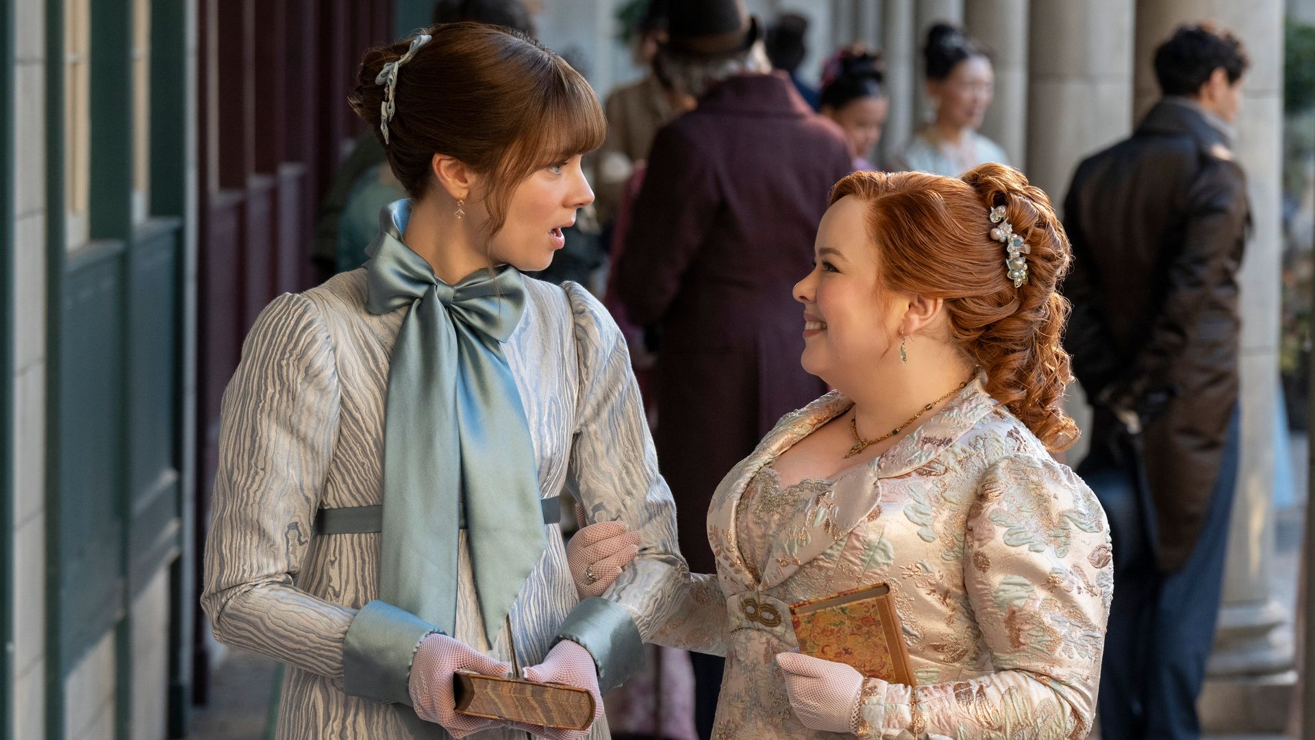 two women dressed in period clothing walking arm in arm