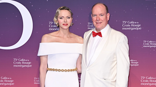 Princess Charlene in a white dress with Prince Albert in a white tuxedo with red bowtie