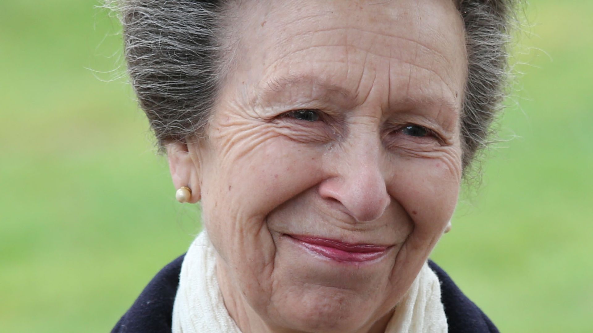 The Princess Royal in a white scarf smiling at King Charles' boarding school