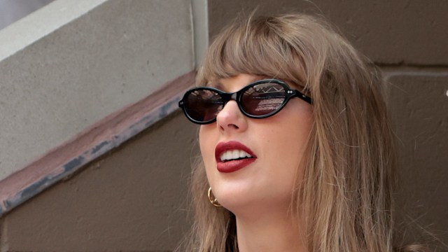 Taylor Swift smiling in sunglasses and a gingham dress