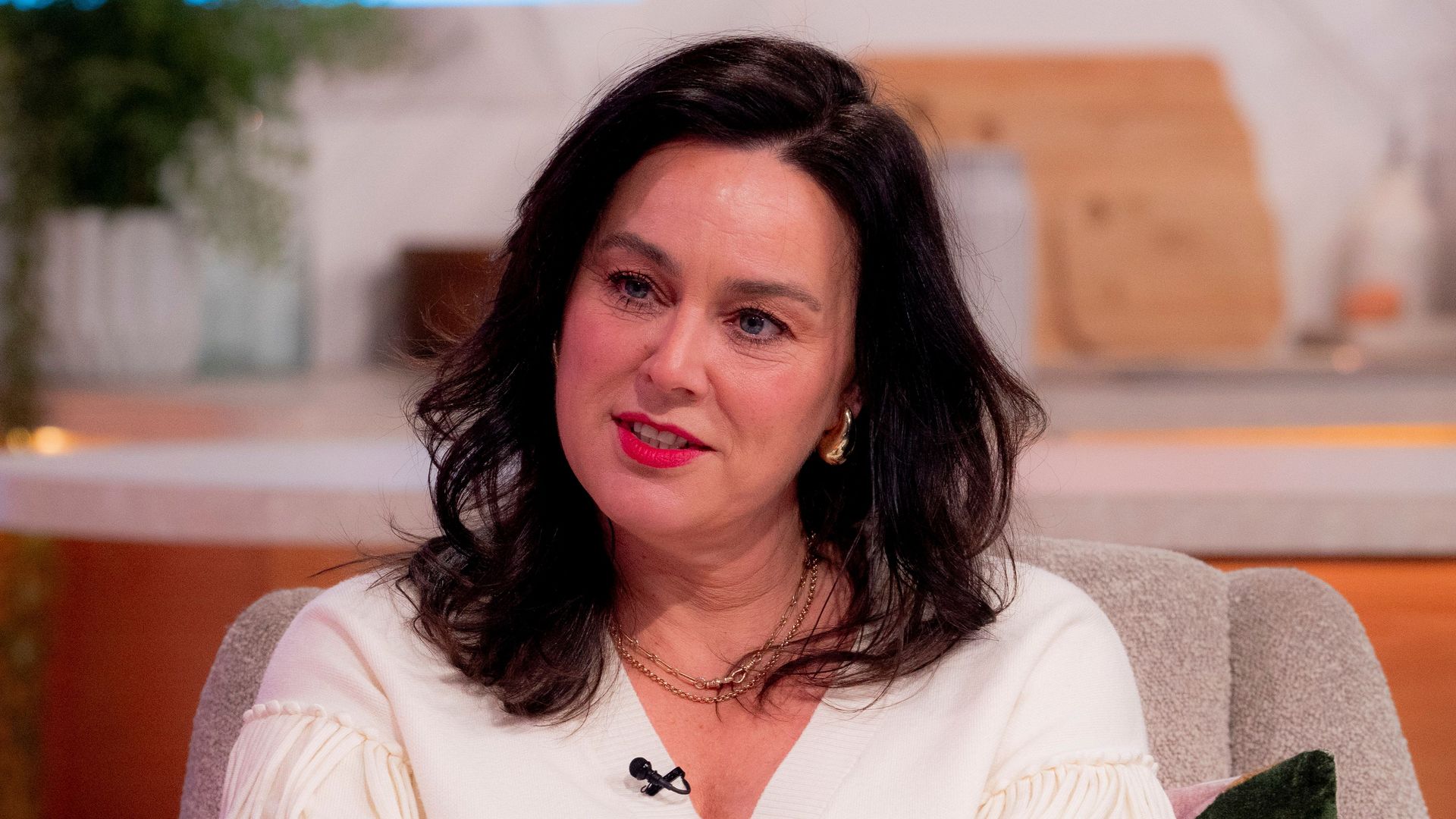 brunette woman in white cardigan in tv studio