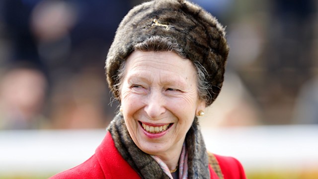 Princess Anne smiling in a red coat and furry hat