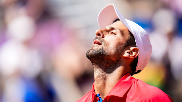 Novak Djokovic wearing a white cap looking into the air at the olympics