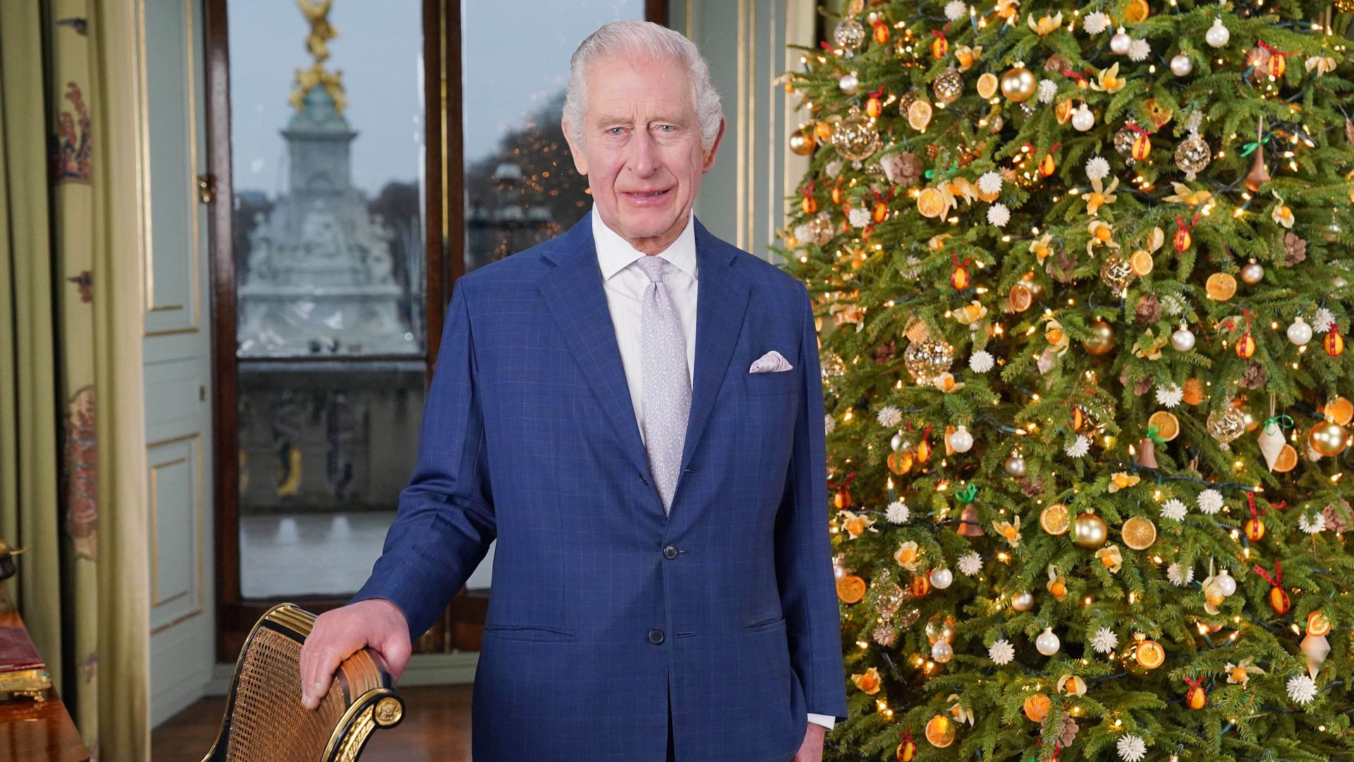 King Charles in a blue suit next to a Christmas tree