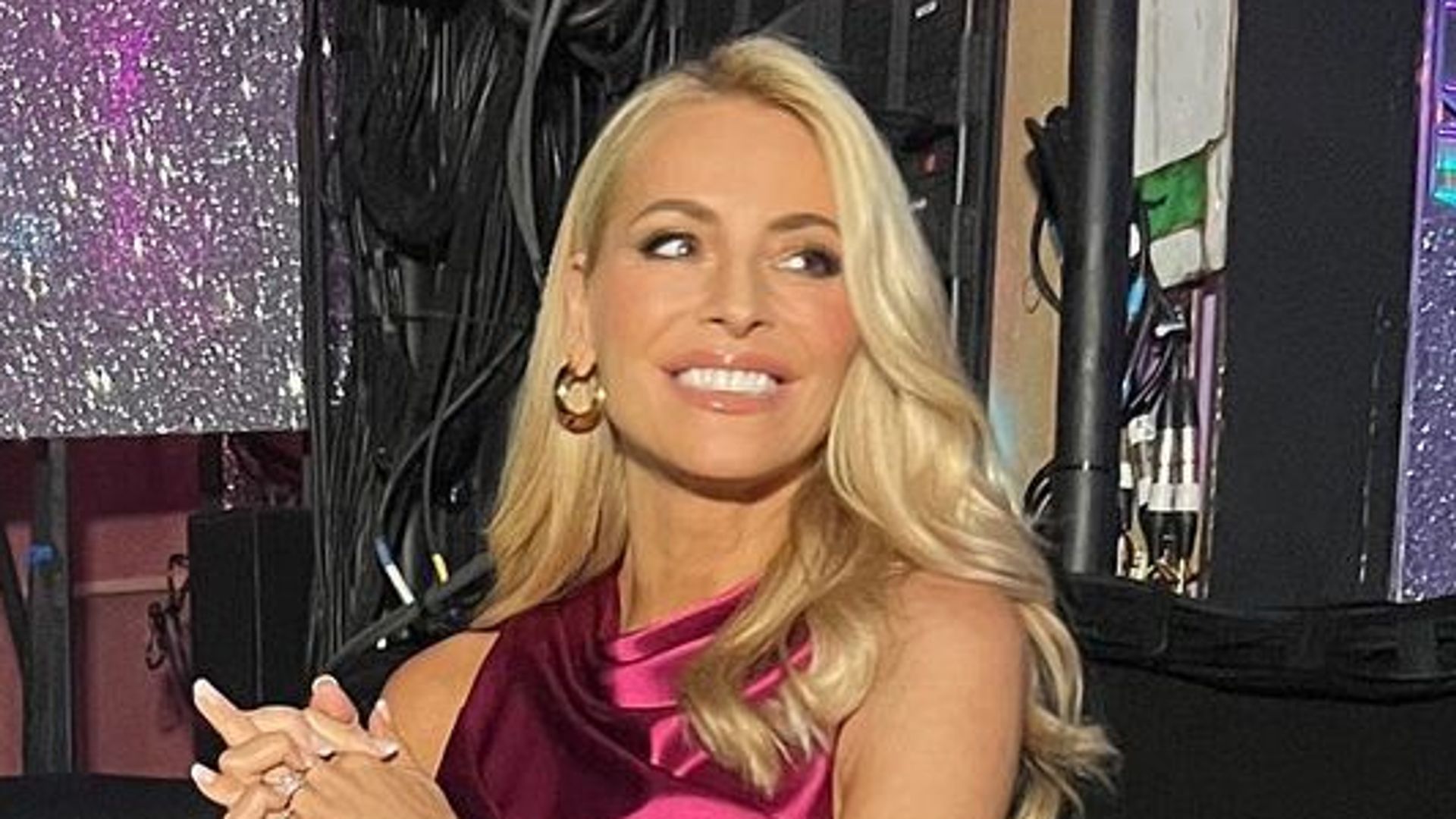 Tess Daly wearing pink satin dress and gold hoop earrings on Strictly 