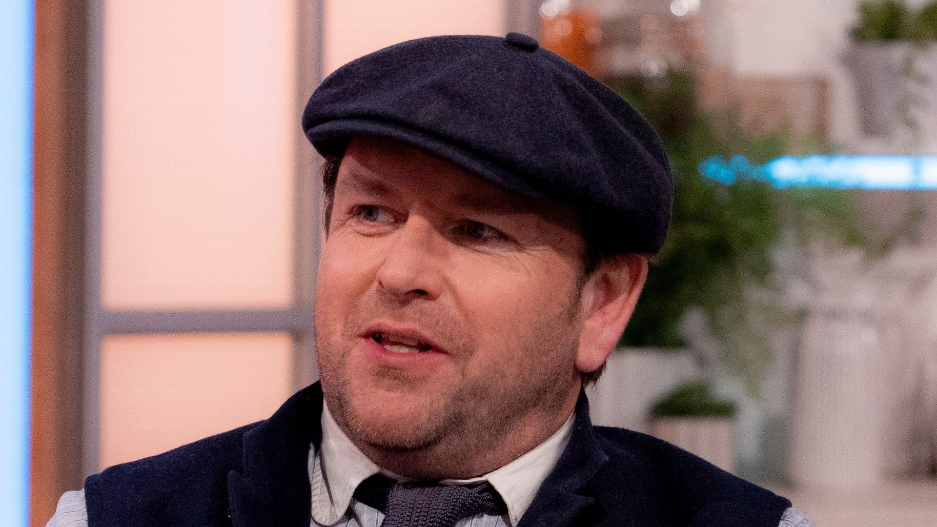 man talking on chat show in waistcoat and hat