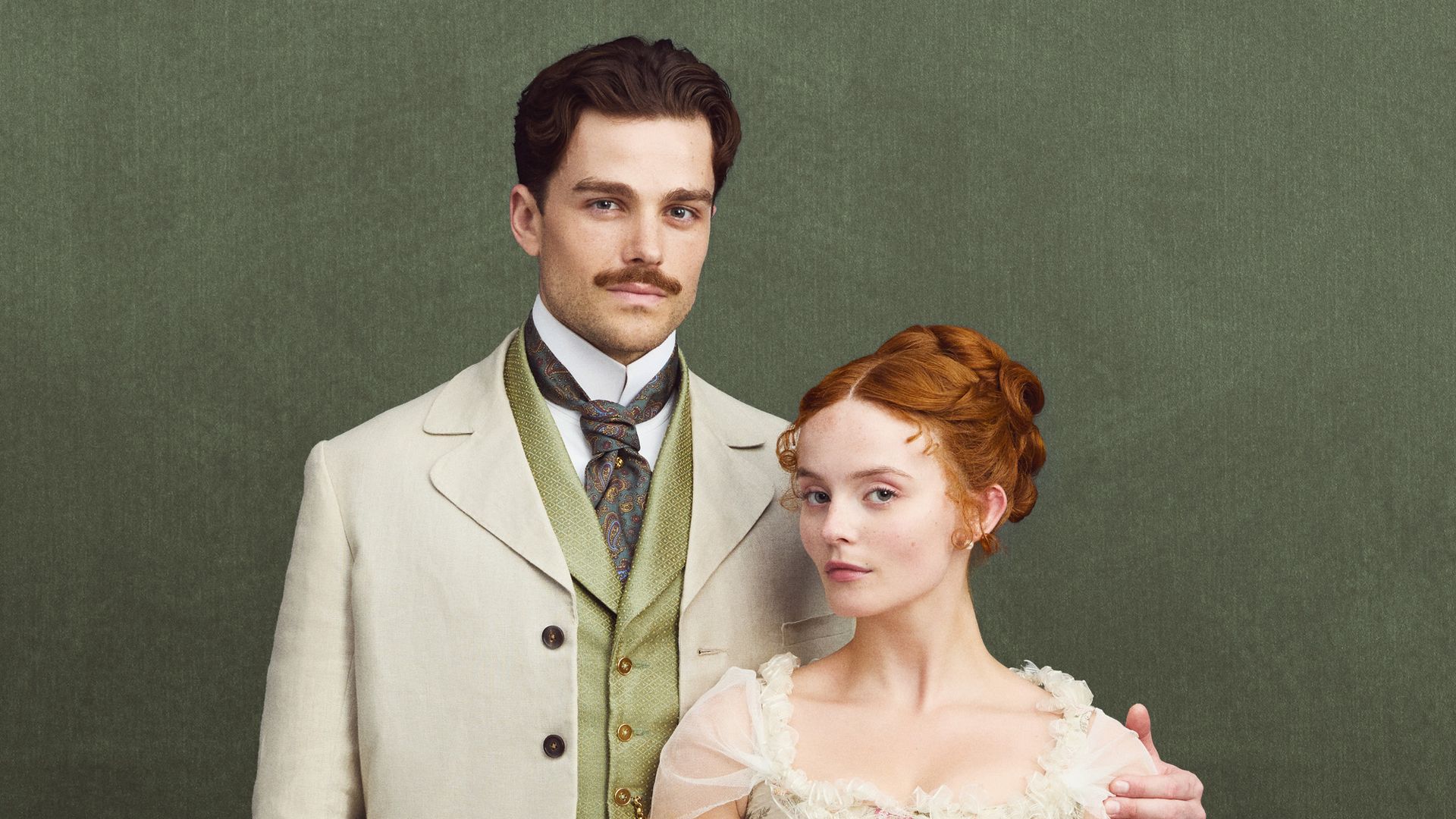 man in suit and woman in period dress against green background