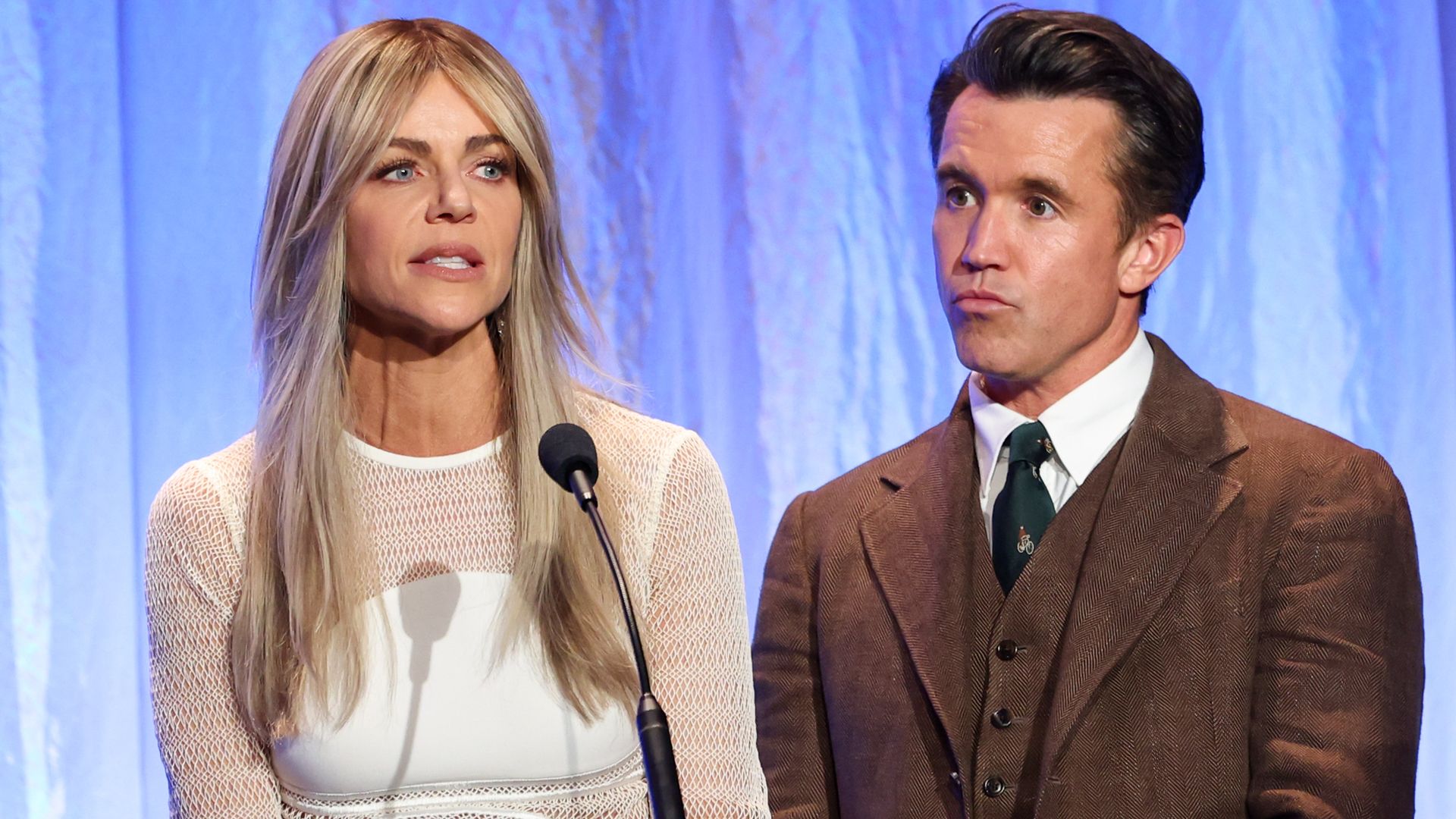 kaitlin olson speaking at podium on stage standing next to rob mcelhenney