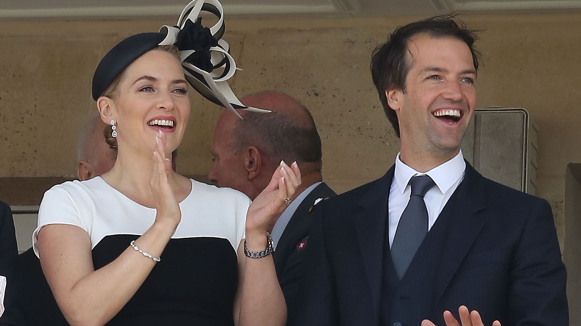 Kate and Edward at a balcony smiling and clapping while watching horse racing