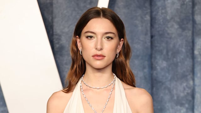 Eve Jobs wearing white dress while looking directly at camera standing on red carpet at vanity fair oscars party