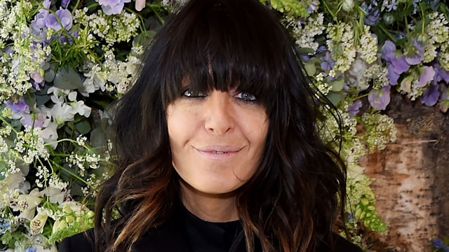 Claudia Winkleman in a black outfit with flowers in the background