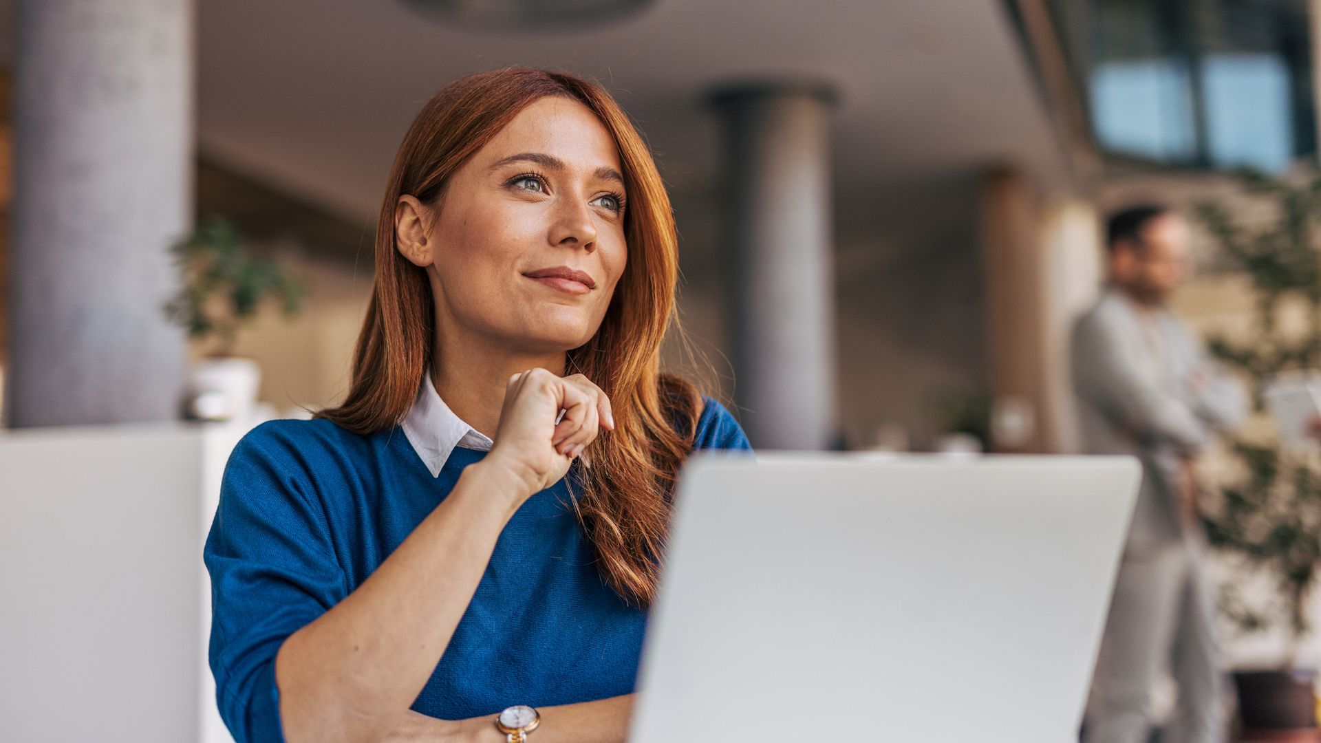 A portrait of a pensive woman sitting at a desk in the office.