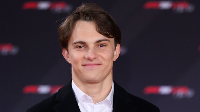 Oscar Piastri smiling in a long coat