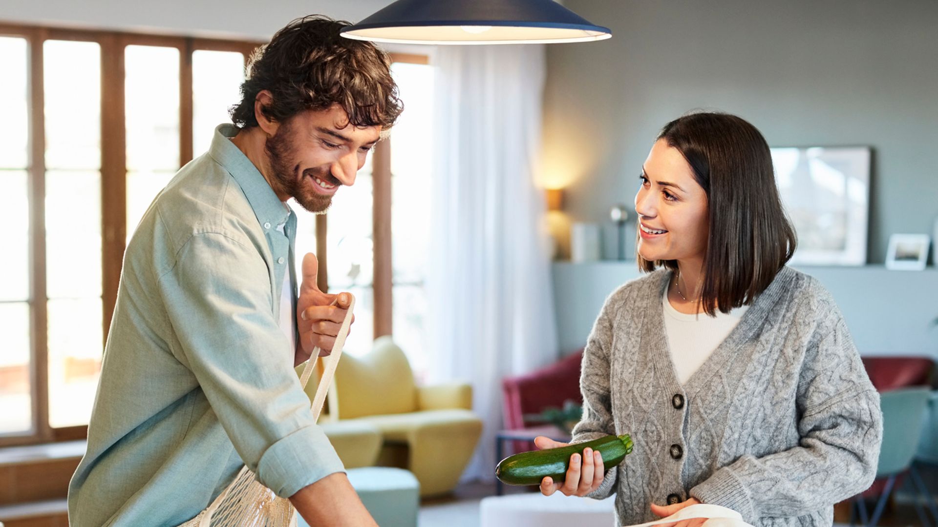 Mid adult couple unpacking vegetables at kitchen island. Man and woman are at home. They are spending time together.