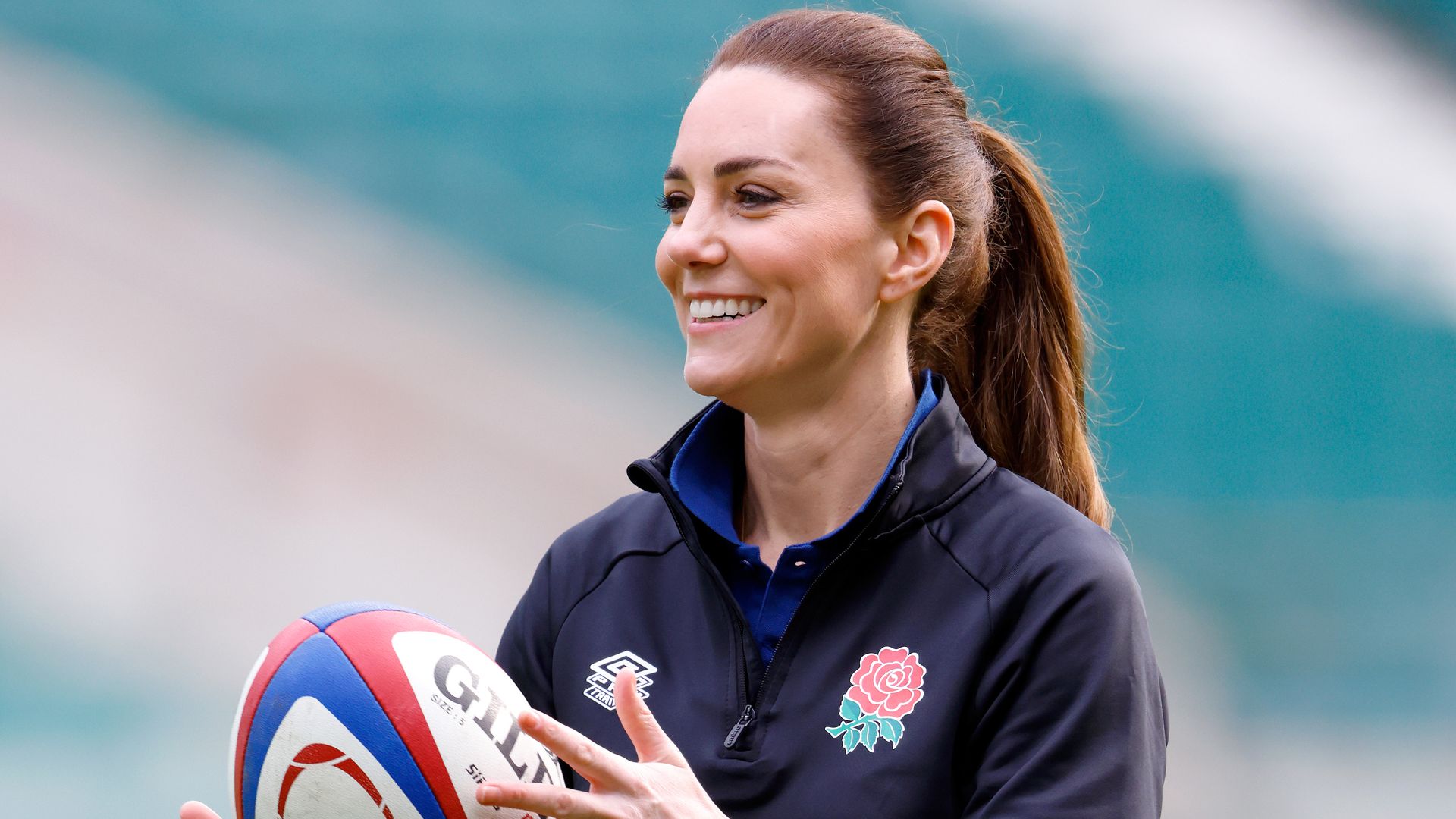 Kate in sports gear throwing rugby ball