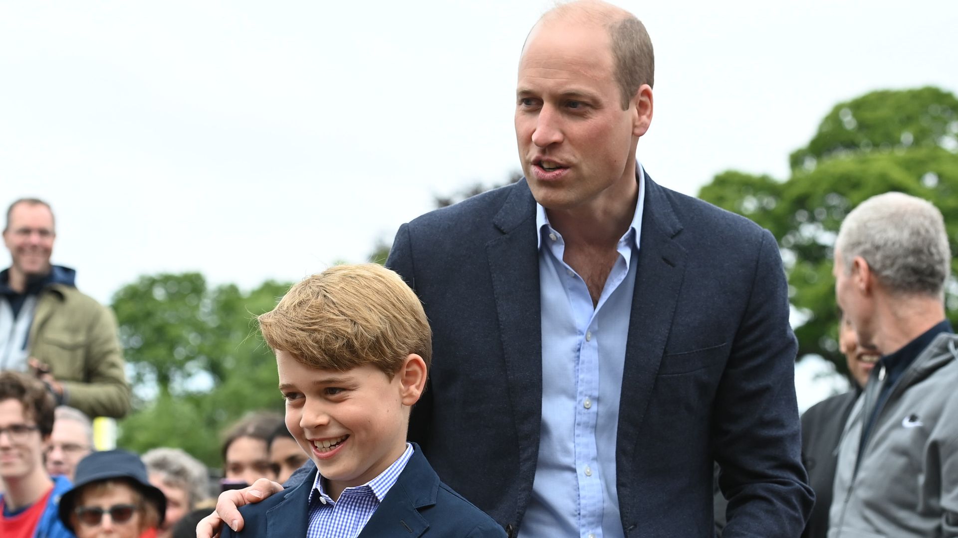 Prince William standing behind Prince George